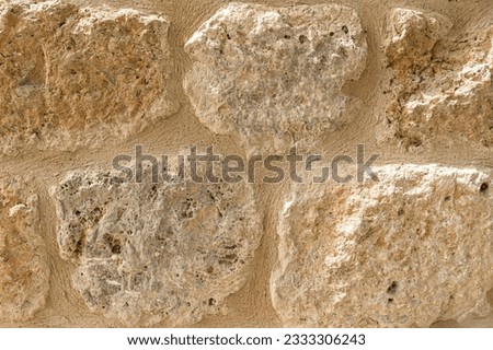 Old beige stone wall background texture close up. Old castle wall surface, antique natural stonewall