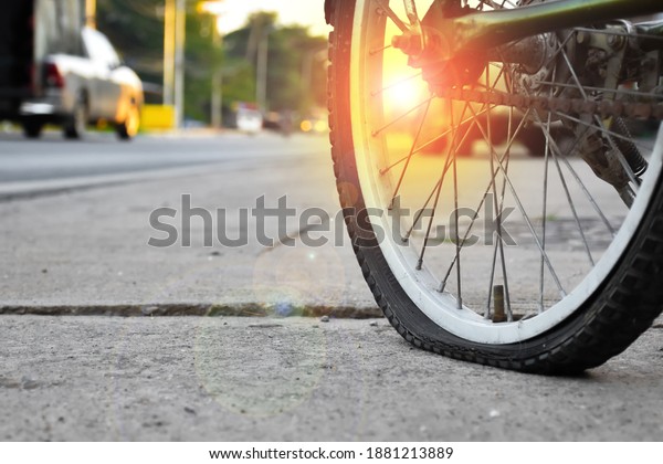Old bicycle flat tire parked by\
the rural road and waited to fix with sunlight in the\
sunset