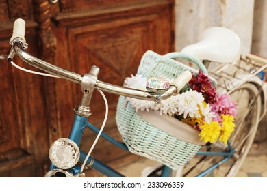 Old Bicycle With Flowers In Metal Basket On Brown Door Background