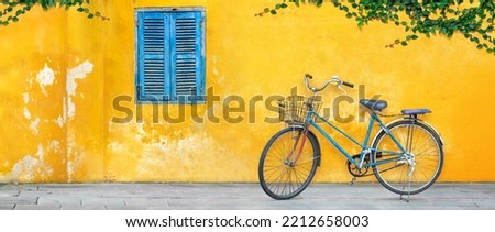 Old bicycle parking against yellow wall in Vietnam