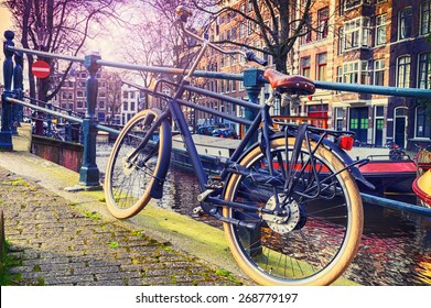 Old bicycle standing next to canal. Amsterdam cityscape
