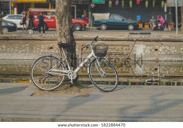 An old\
bicycle that was leaning against a tree beside a canal around the\
city was warm and simple. Retro concept of an old bike. Old\
fashioned values are memories of the old\
days.