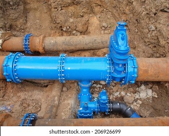 Old big drink water pipes joined with new blue valves and new blue joint members. Finished repaired piping waiting for covering by clay. Extreme kind of corrosion, metal corroded texture.