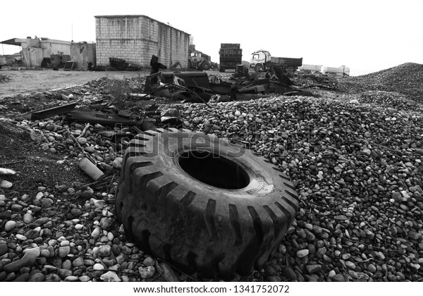 old big heavy truck, dozer tire b&w and\
rusty metals on gravels