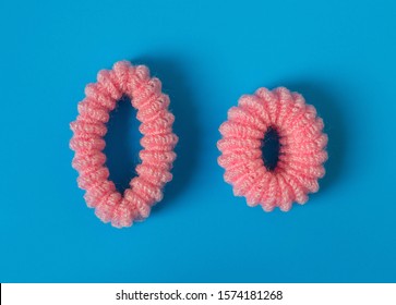 Old big and new small pink elastic hair band. Blue background, close-up.