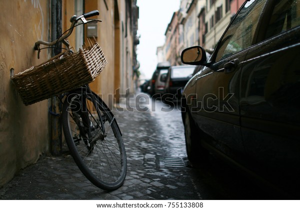 Old bike on a street lined with parked cars in
Rome, Italy.