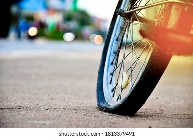 An Old Bike That Has Back Flat Tire Parked By The Urban Road In The Evening Of The Day And Waited To Fix Later. Colour And Lens Flare Edited. Soft Focus