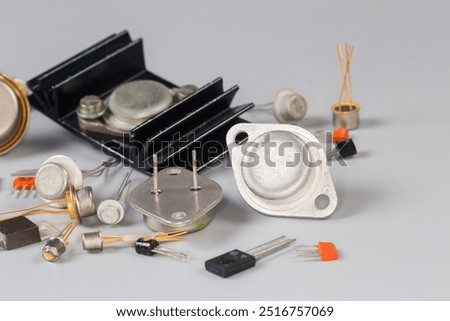 Old bipolar and field-effect transistors various purpose in different metal, ceramic and plastic packages on a gray surface, fragment close-up in selective focus
