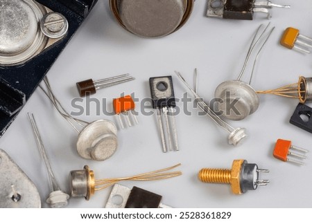 Old bipolar and field-effect transistors various purpose in different metal, ceramic and plastic packages on a gray surface, fragment close-up in selective focus