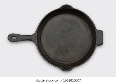 Old black cast iron frying pan or skillet on a white background viewed from above