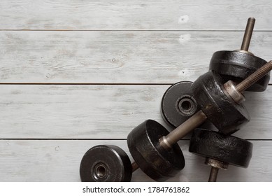 Old Black Dumbbells On A Wooden Floor Background. Simple Gym Flat Lay Background With Copy Space.