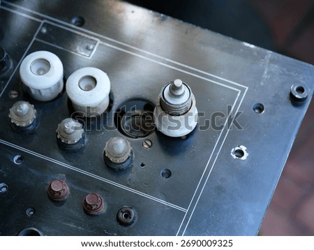 Old black electrical panel with white ceramic plug fuses and small lamps