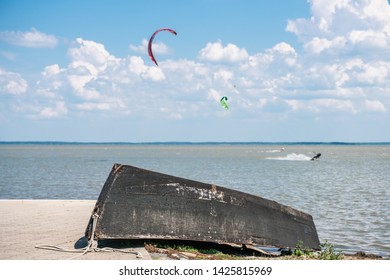 Old Black Fishing Boat On The Shore. In The Background Kitesurfer.