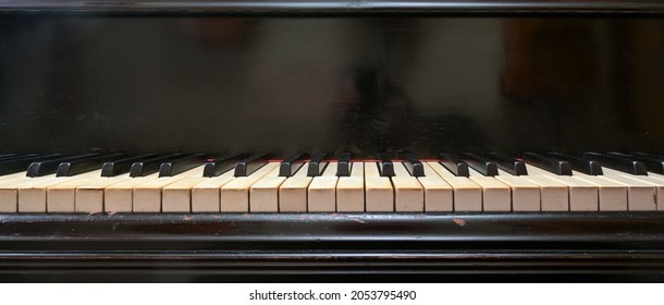 Old black grand piano keyboard with keys from ivory and ebony, part of a musical instrument in panoramic format, copy space, selected focus, narrow depth of field - Powered by Shutterstock