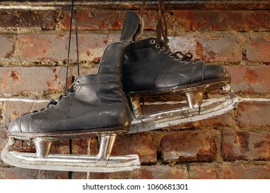 Old Black Hockey Skates Hanging On The Brick Wall