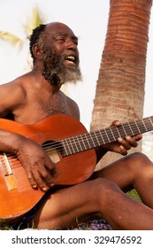 Old Black Man Play Guitar On A Tropical Island