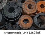 Old black sheet rubber and two rolls of brown rubber on top, rolled into rolls, top view. rubber waste.