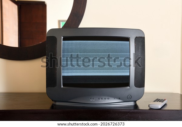 An old\
black TV with noise on the screen sits on the bedside table in the\
apartment. Vintage TVs 1980s 1990s\
2000s.