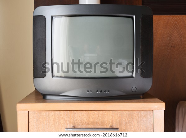 An old black TV is on the bedside\
table in the apartment. Vintage TVs 1980s 1990s 2000s.\
