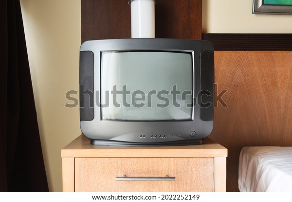 An old black TV is on the bedside\
table in the apartment. Vintage TVs 1980s 1990s 2000s.\
