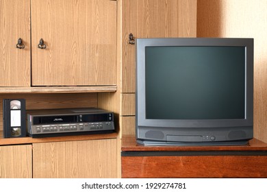 Old Black TV And VCR Set Against Old Furniture From The 1980s And 1990s.