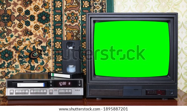Old black vintage TV with\
green screen to add new images to the screen, VCR on wallpaper\
background.