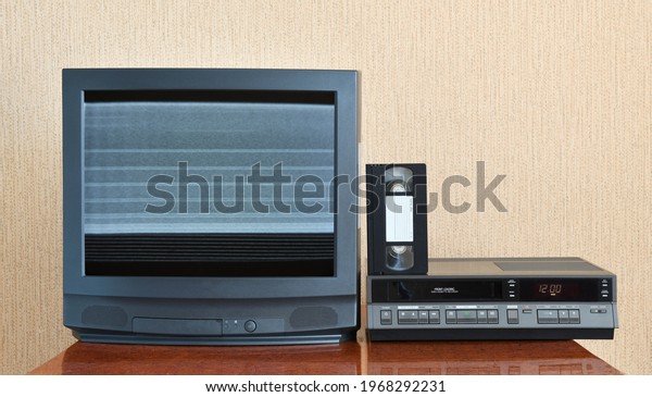Old black vintage TV with noise and\
interference on screen 1980s 1990s 2000s to add new images to the\
screen, VCR on wallpaper\
background.