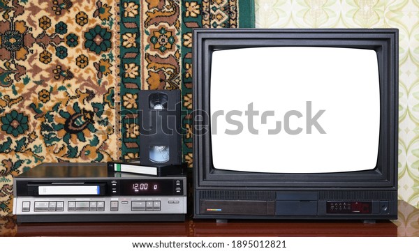 Old black vintage TV with white screen to add\
new images to the screen, VCR against the background of old carpet\
and wallpaper.
