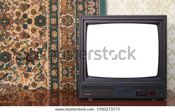 Old\
black vintage TV with white screen to add new images to the screen\
TV set against wallpaper and carpet from\
1980-1990.