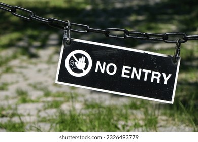 Old black and white sign with warning symbol and the inscription “No entry” in uppercase letters hanging outside on an old chain, copy space - Shutterstock ID 2326493779