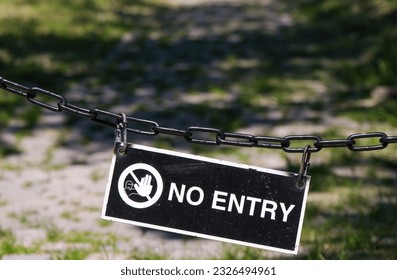 Old black and white sign with warning symbol and the inscription “No entry” in uppercase letters hanging outside on an old chain, copy space - Shutterstock ID 2326494961