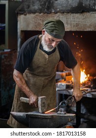 Old blacksmith working metal with hammer on the anvil in the forge