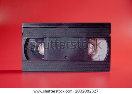 An old blank VHS tape (archival medium for videos and movies), isolated on a shiny red background.
