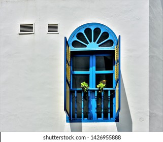 Old blue arched window with wooden shutters and balustrade on the side of a traditional shop house in historic Little India, Singapore