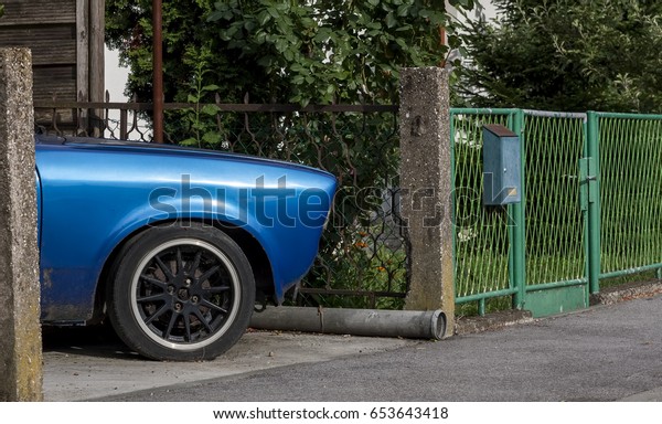 An old blue car in the yard, surrounded by plants,
vintage car 