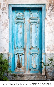 Old Blue Door With Chipped Paint In A Weathered House Wall