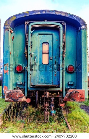 Old blue passenger carriage with front door on disused train tracks at old station, rusty and corroded metal, docking stops, cloudy autumn day in As, Limburg Belgium