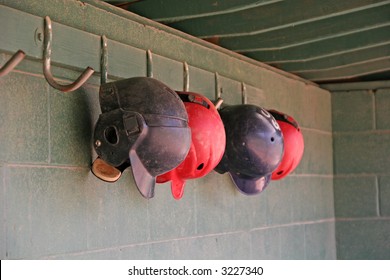 Old blue and red batting helmets hanging in a dugout