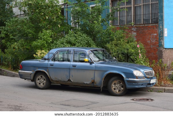 An\
old blue Soviet car in the courtyard of a residential building,\
Podvoysky Street, St. Petersburg, Russia, July\
2021