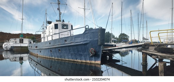 Old Blue Tug Ship Close-up. Yachts And Boats Moored To A Pier In Yacht Marina On A Clear Summer Day. Riga, Latvia. Vacations, Sport, Amateur Recreational Sailing, Fishing, Industry, Traditional Craft