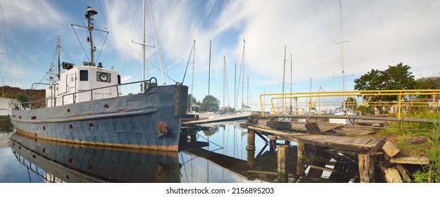 Old Blue Tug Ship Close-up. Yachts And Boats Moored To A Pier In Yacht Marina On A Clear Summer Day. Riga, Latvia. Vacations, Sport, Amateur Recreational Sailing, Fishing, Industry, Traditional Craft