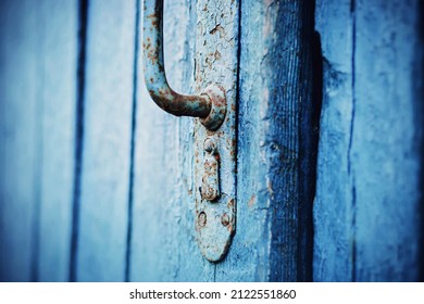 An old blue wooden door with a rusty metal handle. A closed door to the house. The mystery is behind the door. Retro.