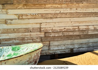 Old boat abandoned on the beach, near a dilapidated wooden shed, close-up, sunlight - Powered by Shutterstock