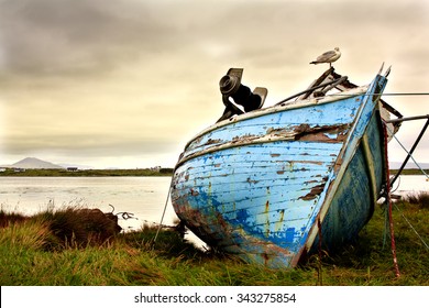 Old boat abandoned on the coastline in Ireland. Moody sky and run-down boat express lonliness and sadness.  - Powered by Shutterstock
