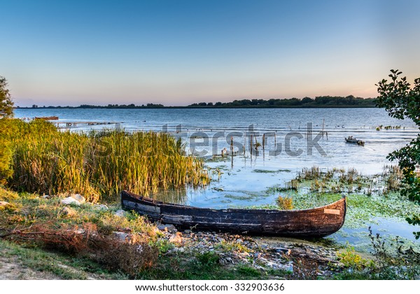 Old boat on\
the water in the lake among the reeds. Bright and calm view with\
wooden boat on the coast in the summer\
.