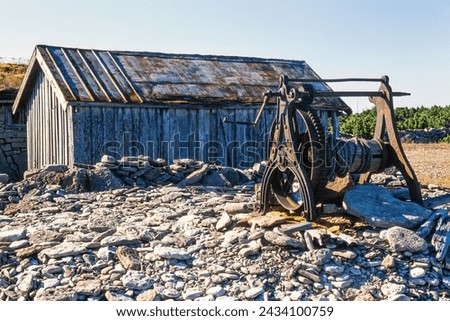 Old boat winch by a wooden shed on the coast