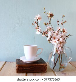 Old Book, Cup Of Coffee Next To Spring White Flowers On Wooden Texture