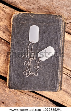Old book and dog tags. Top view, flat lay. Wooden desk background.