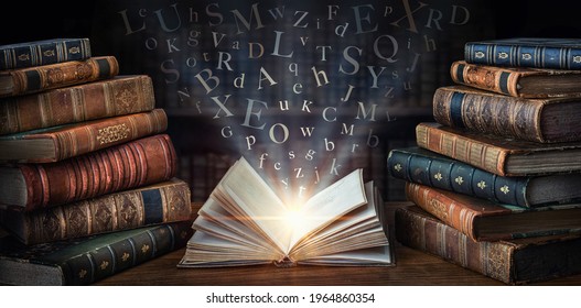 Old book with flying letters and magic light on the background of the bookshelf in the library. Ancient books as a symbol of knowledge, history, memory and information.  - Shutterstock ID 1964860354