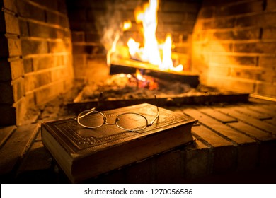 Old book with glasses on it beside fireplace